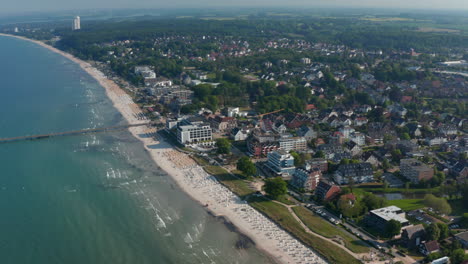 Baltic-sea-coastline-in-Scharbeutz,-Germany.-Aerial-drone-flying-above-tourist-sea-summertime-beach,-dolly-in,-day